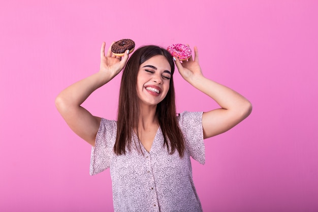 Garota de modelo de beleza tomando rosquinhas coloridas.