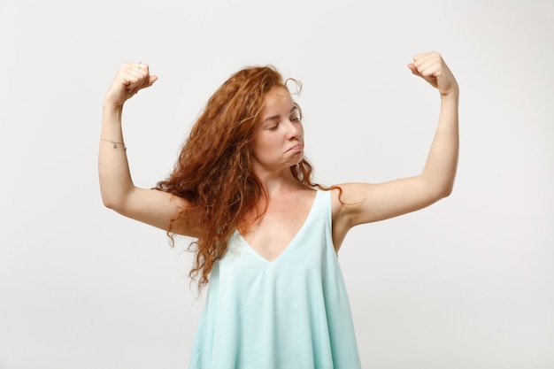 Garota de mulher jovem ruiva forte em roupas leves casuais posando isolado no fundo branco, retrato de estúdio. conceito de estilo de vida de emoções sinceras de pessoas. simule o espaço da cópia. mostrando bíceps, músculos.