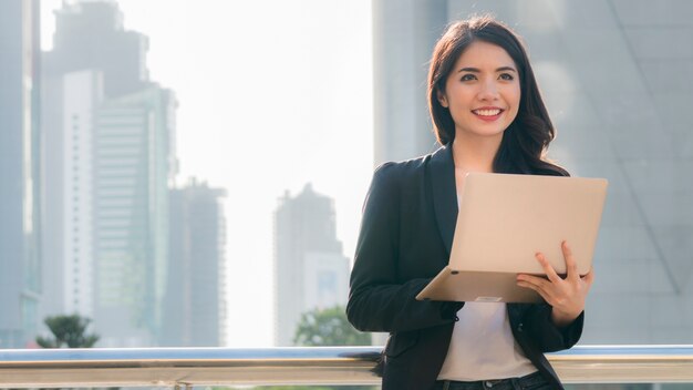 garota de negócios com computador notebook e cidade de fundo