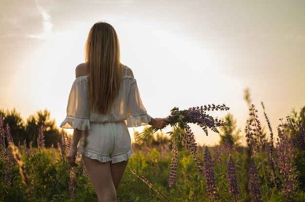 Foto garota de pé geral bege no campo com o buquê de flores