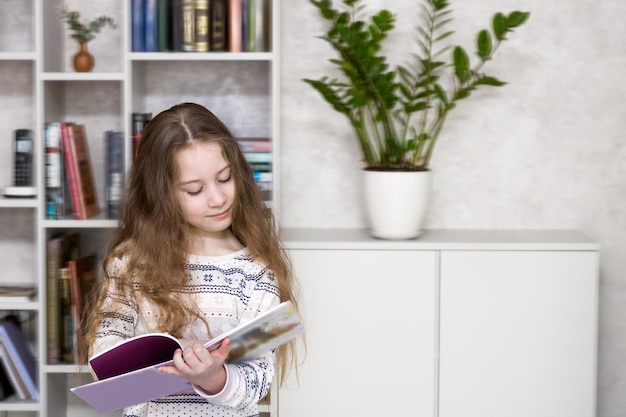 Garota de pijama com cabelo comprido lê um livro perto de uma estante
