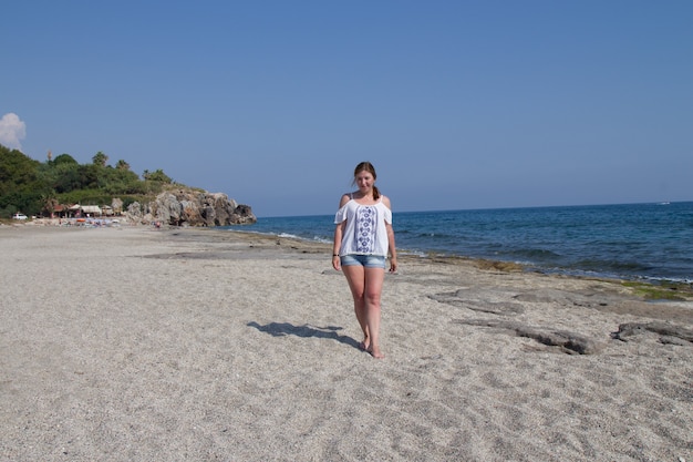 Garota de short e blusa branca na praia à beira-mar ... Mulher ruiva na praia. Um feriado no sul