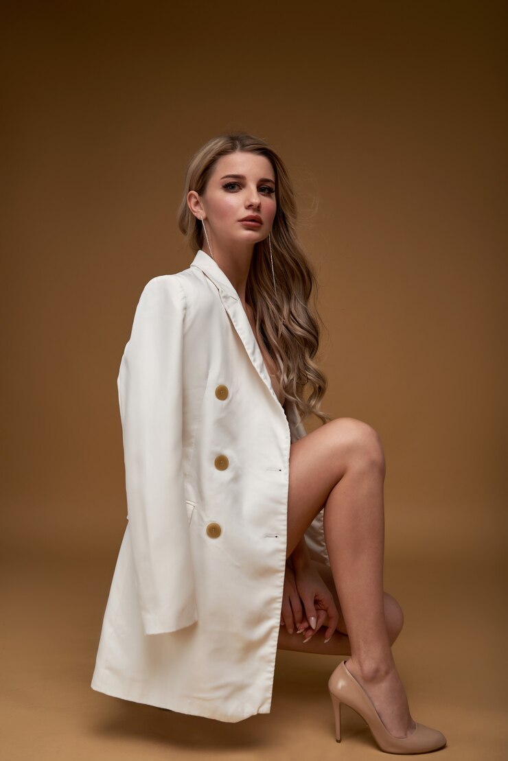 Foto garota de terno com cabelos ondulados e maquiagem posando em uma parede bege moda estilo retrato de corpo inteiro mulher na moda elegante