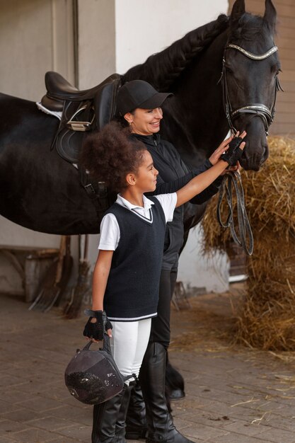 Foto garota de tiro completo aprendendo a andar a cavalo