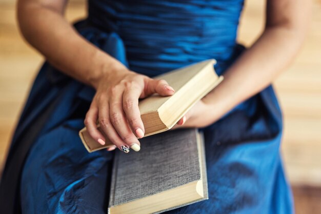 Garota de vestido azul, segurando o livro nas mãos com amor à leitura