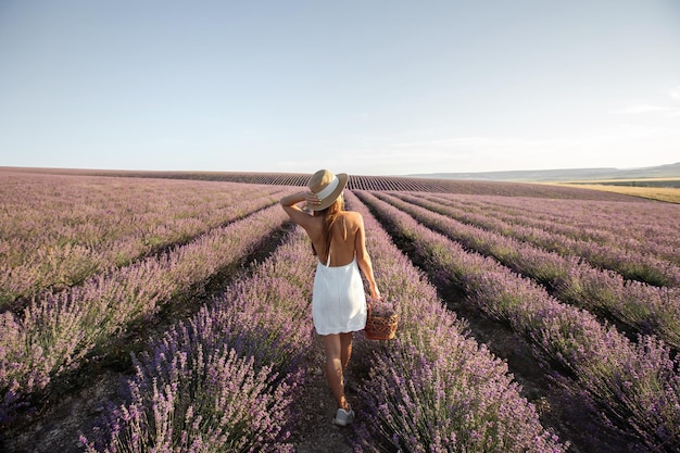 Garota de vestido branco com uma cesta em um campo de lavanda