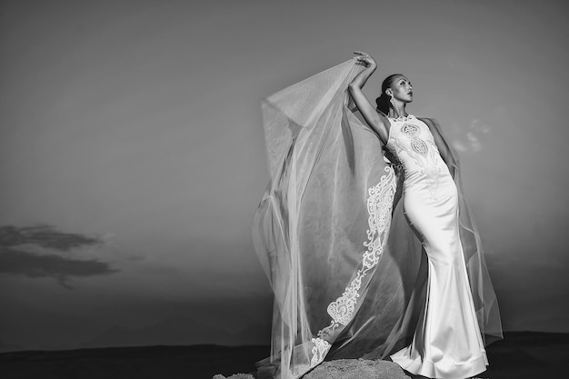 Garota de vestido de noiva ao ar livre no céu noturno Noiva e cerimônia Elegância e modelo de moda Casamento moda e salão de beleza Mulher de vestido branco no pôr do sol