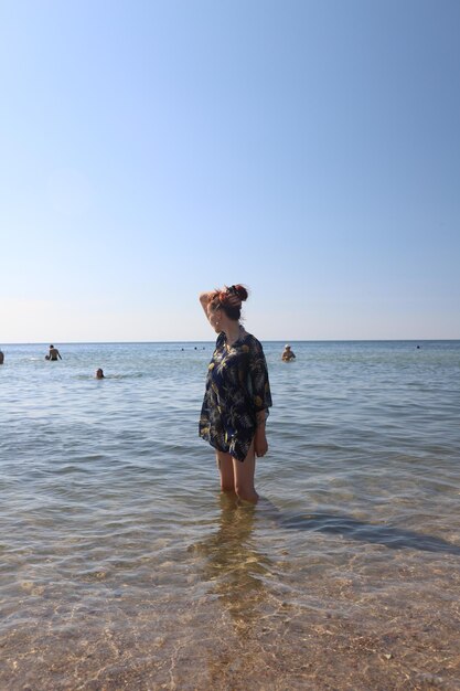 Garota de vestido na praia ensolarada