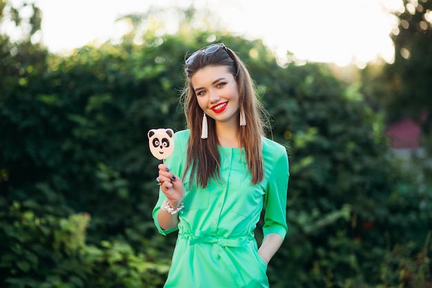 Garota de vestido verde, mostrando o panda de doces na vara.