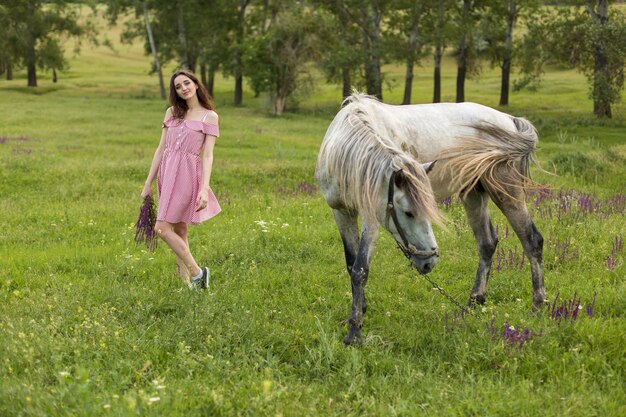 Garota de vestido vermelho na natureza no verão Retrato de uma linda garota com um cavalo