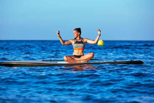 Garota de yoga sobre sup stand up surf board