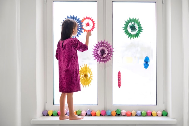 Garota decora as janelas com decoração de Natal