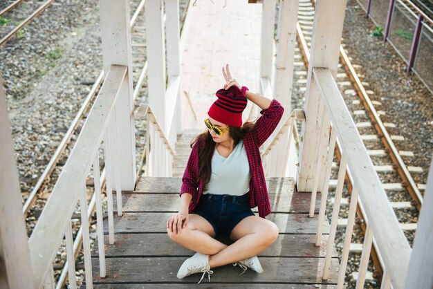 Garota descolada asiática usa óculos de sol posando para tirar uma foto na escada de madeira estilo de vida da mulher moderna, pessoas tailandesas no estilo hippie