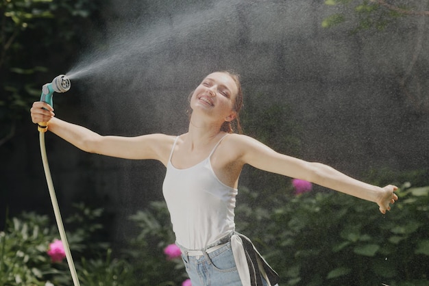 Garota desfrutando de água no calor do verão no jardim