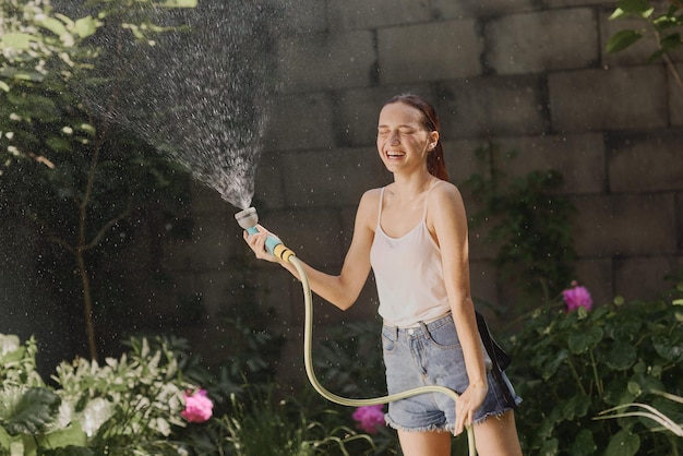 Garota desfrutando de água no calor do verão no jardim