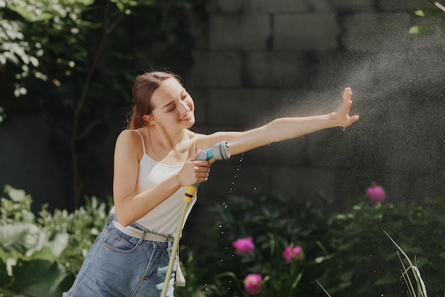Garota desfrutando de água no calor do verão no jardim