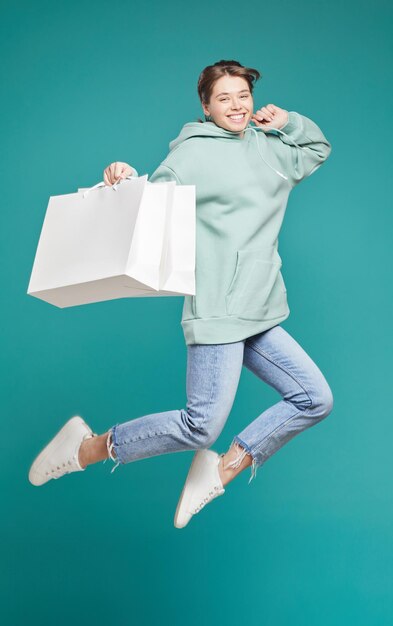 Garota despreocupada pulando com sacolas de compras