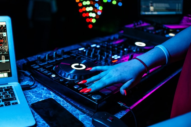 Garota DJ mistura música com as mãos em um mixer de música em uma boate em uma festa