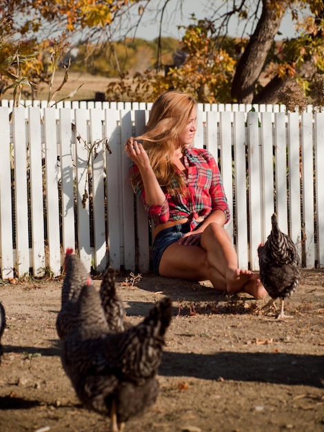 Garota do campo cercada por galinhas.