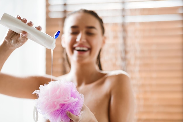 Garota do conceito de higiene colocando gel de banho no puff