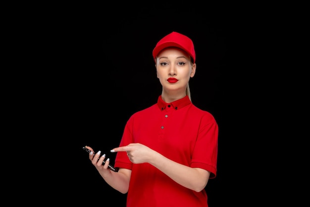 Garota do dia da camisa vermelha segurando o telefone em um boné vermelho vestindo camisa e batom brilhante