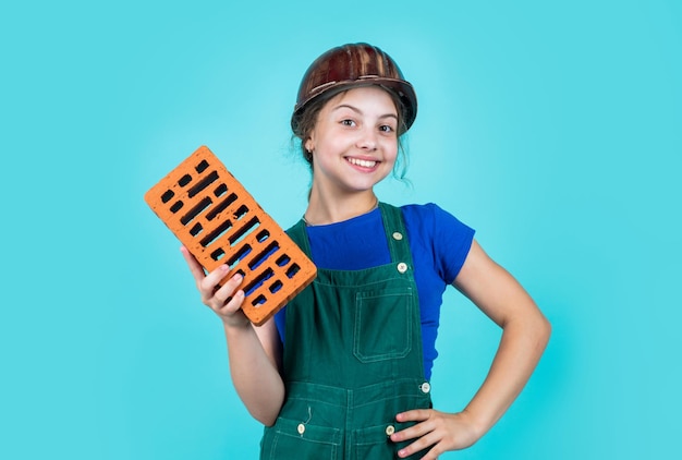 Garota do dia internacional dos trabalhadores no capacete joga construtor com tijolo construindo uma casa Garoto constrói engenheiro de construção adolescente é trabalhador da construção Artesão profissional ou trabalhador