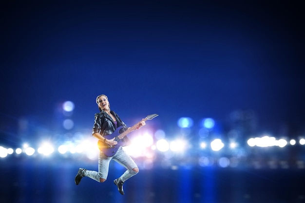 Garota do rock jovem e bonita tocando guitarra elétrica. Mídia mista