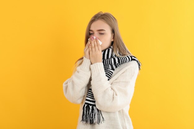 Garota doente em fundo amarelo, conceito de frio sazonal