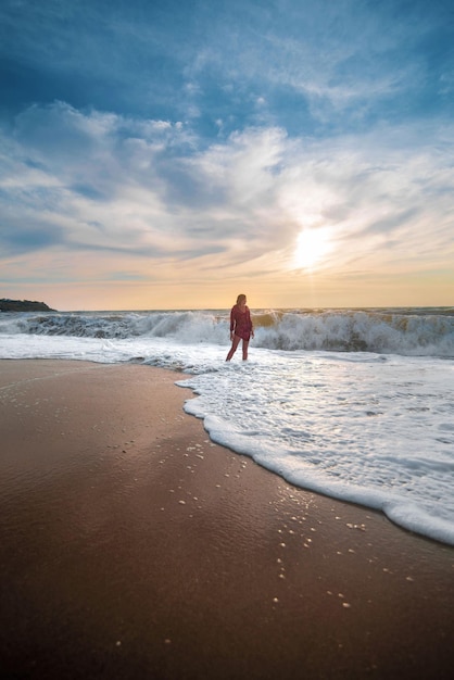 Garota durante uma tempestade na praia nas ondas