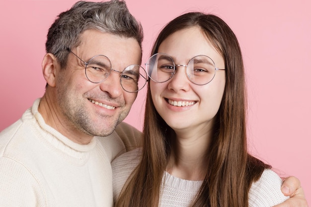 Garota e cara de óculos redondos em um fundo rosa