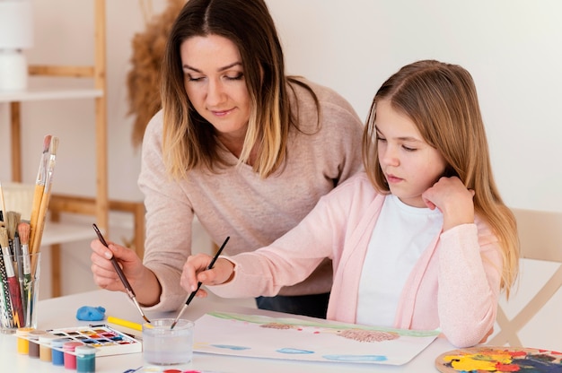 Garota e mulher em plano médio pintando