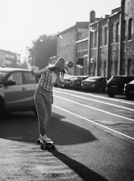 Garota elegante anda de skate na cidade ao pôr do sol