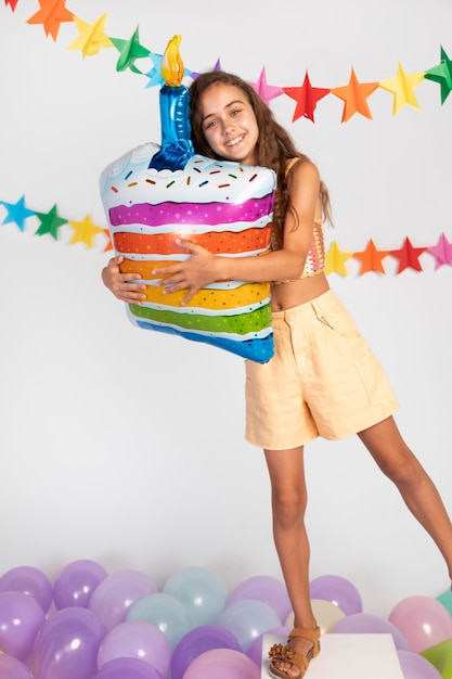 Garota em cena segurando um balão de bolo