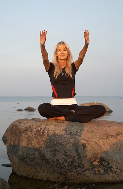 Foto garota em forma meditando na praia