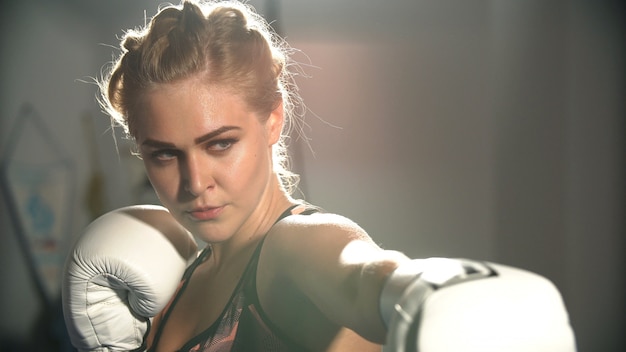 Garota em luvas de boxe no treinamento de boxe.