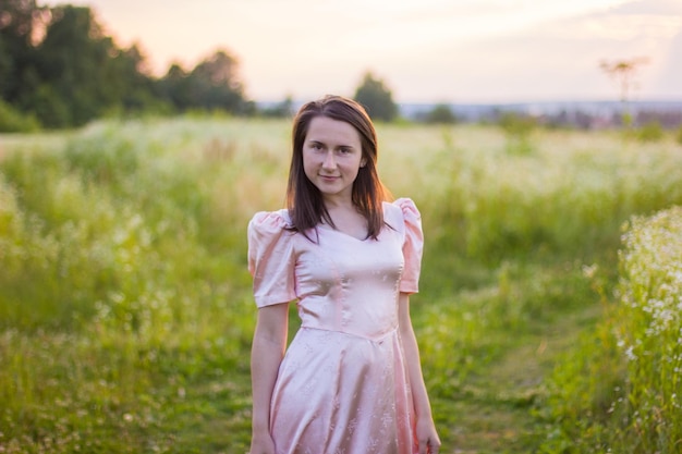 Garota em pé no campo com um vestido rosa