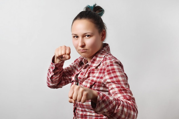 Garota em postura de boxe com os punhos cerrados em cinza claro