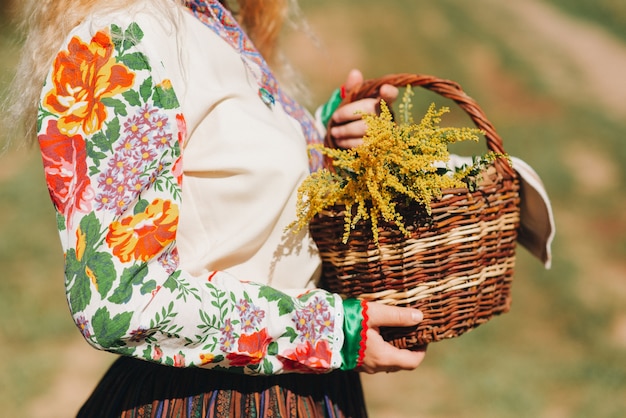 Garota em traje nacional com uma cesta de flores, close-up. vestido nacional