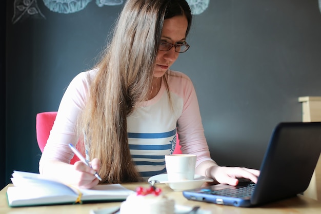 Garota em um café tomando uma xícara de café com o notebook