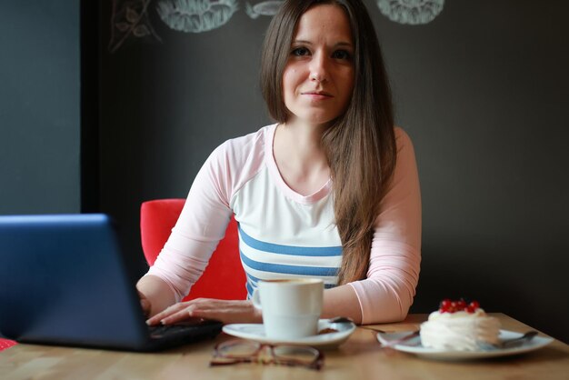 Garota em um café tomando uma xícara de café com o notebook