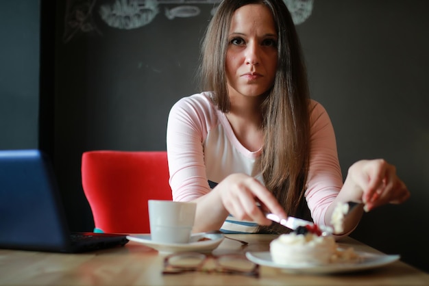 Garota em um café tomando uma xícara de café com o notebook