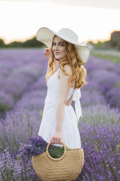Garota em um campo de lavanda Mulher em um campo de flores de lavanda ao pôr do sol em um vestido branco França Provence