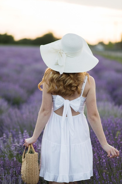 Garota em um campo de lavanda Mulher em um campo de flores de lavanda ao pôr do sol em um vestido branco França Provence