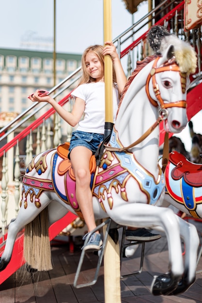 Garota em um carrossel com cavalos em uma feira