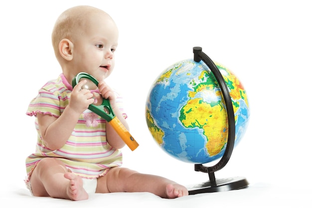 Garota em um fundo branco à mesa com um globo e notebooks