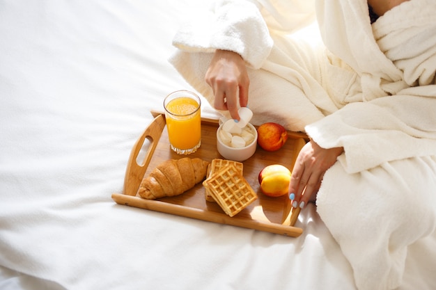 Garota em um roupão tomando café da manhã na cama