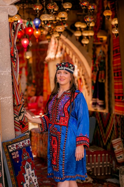 Garota em um traje nacional turco azul fotografado em uma loja de tapetes