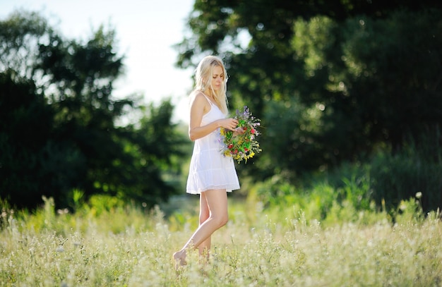 Garota em um vestido branco e com uma coroa de flores na mão