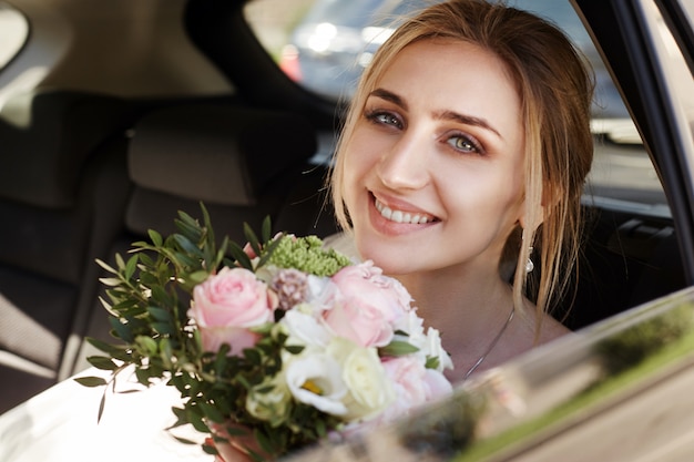 Garota em um vestido de noiva, segurando um buquê de flores nas mãos