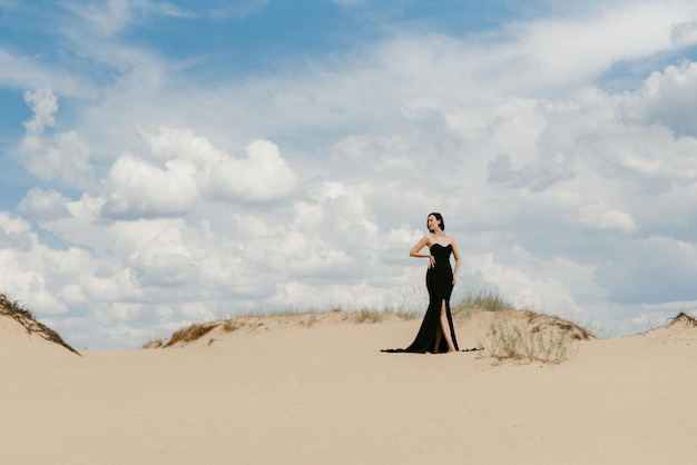 Garota em um vestido longo preto em um deserto arenoso